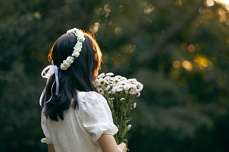 花与少女夕阳下拿着花的少女背影背景