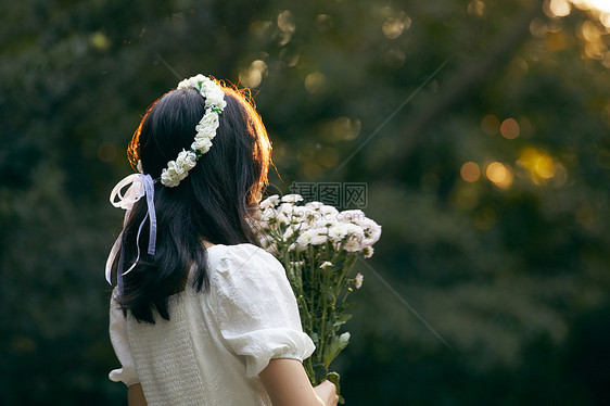 夕阳下拿着花的少女背影图片