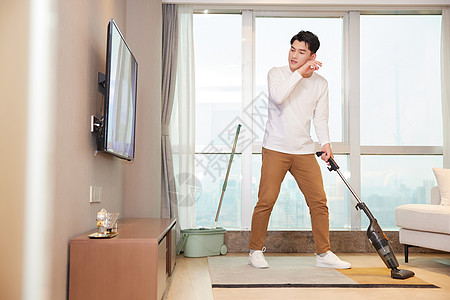 年轻男性居家使用吸尘器清洁地毯背景图片