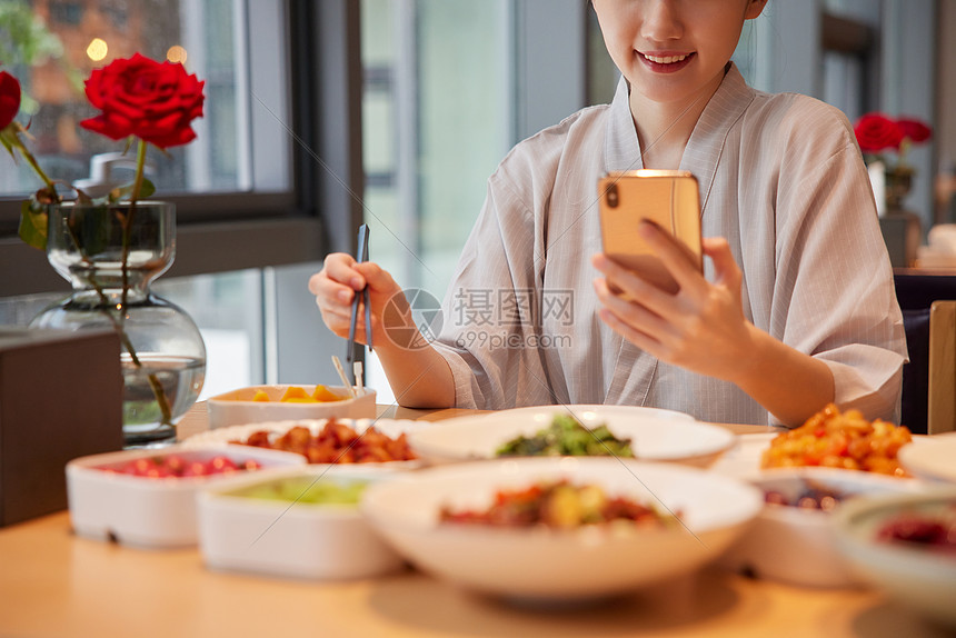 青年女性在汤泉馆吃饭玩手机特写图片