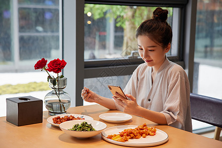 在汤泉馆美食区吃饭玩手机的青年女性图片