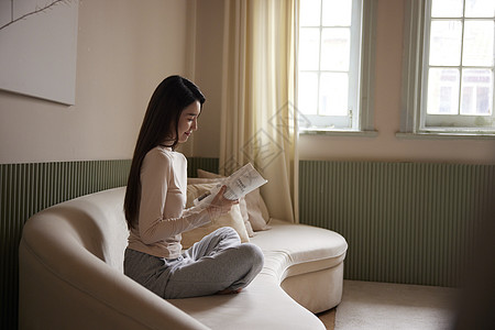 知性美女坐在沙发上看书休息图片