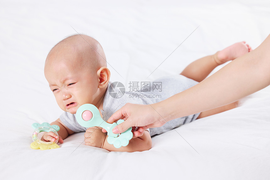 手拿玩具逗哭泣的宝宝图片