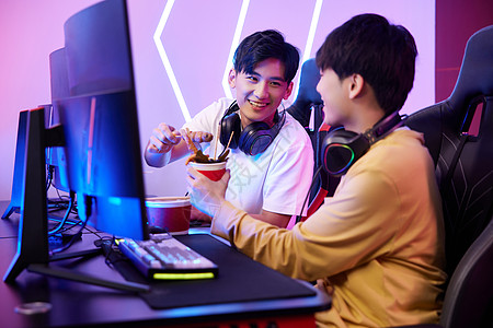 青年男性网吧里打电脑游戏吃关东煮背景图片