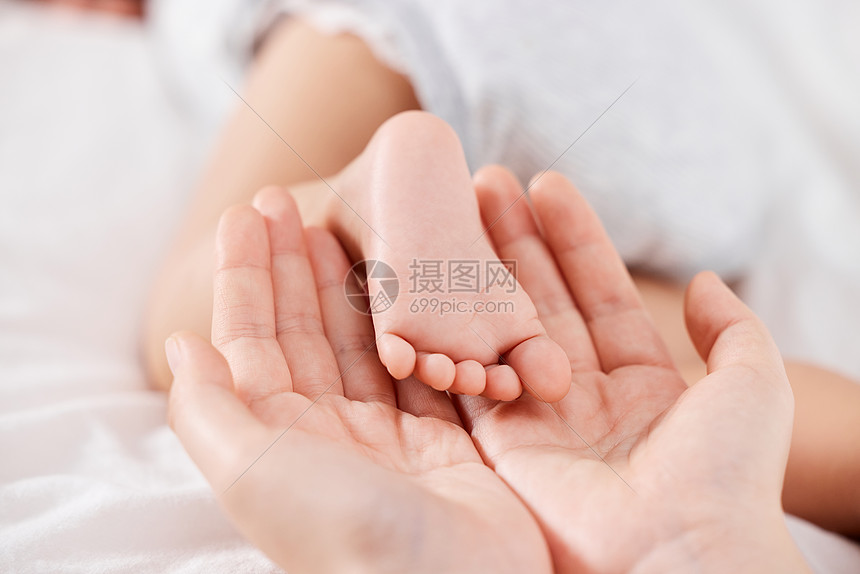 妈妈手托新生婴儿的小脚特写图片