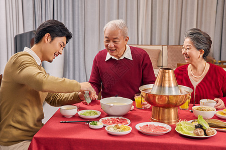 男青年年夜饭给父亲倒酒高清图片