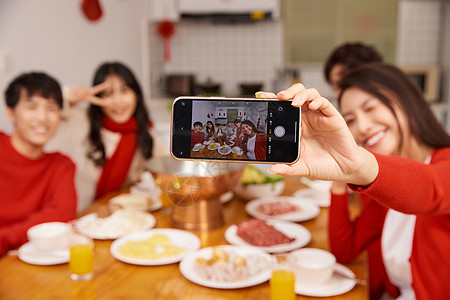 年轻人拿手机年轻人新年聚会吃饭拿手机自拍特写背景
