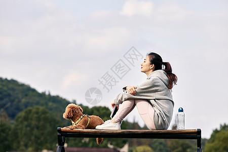 运动的人坐在长椅上的运动少女和萌宠泰迪背景