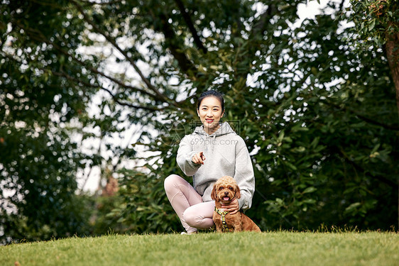 看着镜头的萌宠泰迪和运动少女图片