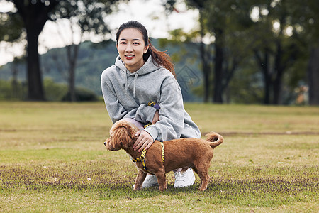 在公园里和泰迪一起玩耍的运动少女背景