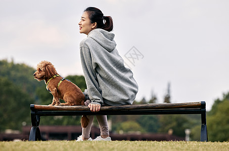 坐在长椅上放松的运动少女和萌宠泰迪图片