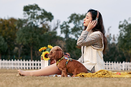 美女在草地上听着音乐抚摸狗图片