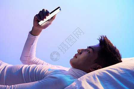 年轻男性躺着使用手机体验智能生活高清图片