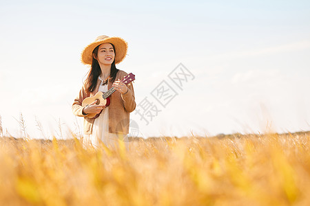 在稻田里弹奏尤克里里的女性图片