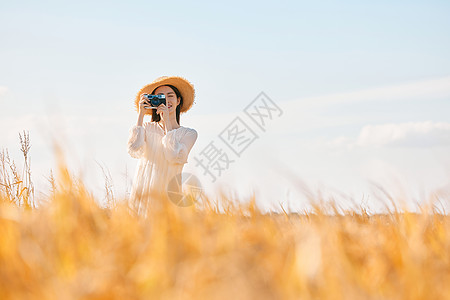 乐在金秋拿着照相机站在稻田里的女性背景