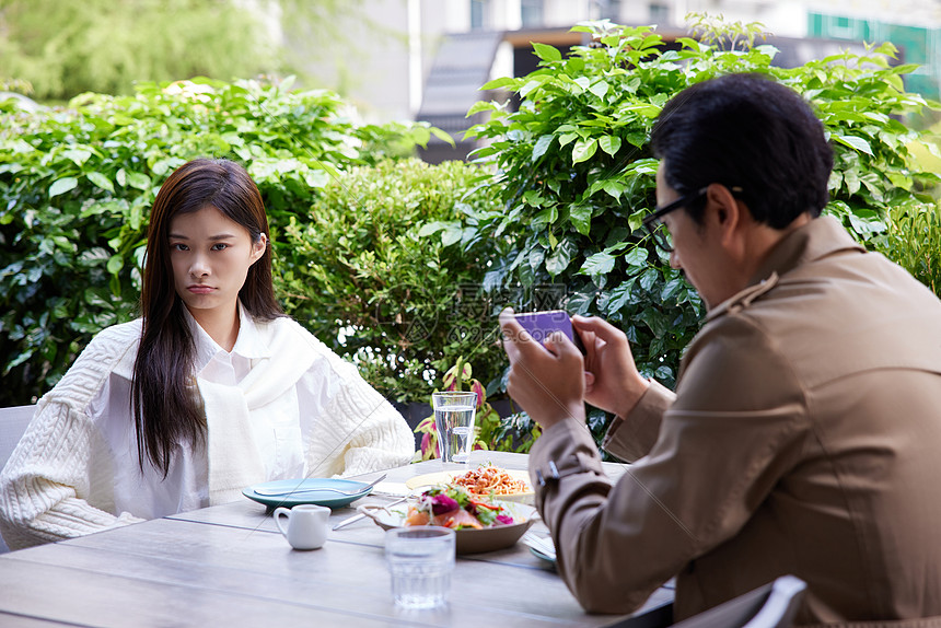 女性不高兴男性约会吃饭玩手机图片