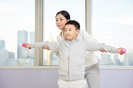 老师纠正手拿哑铃的小男孩图片