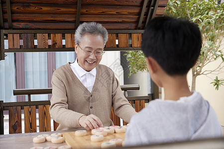 老年娱乐爷爷教孙子户外下象棋背景