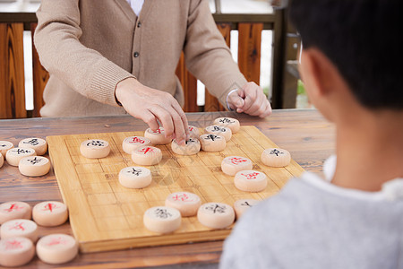 老年娱乐爷爷教孙子户外下象棋背景