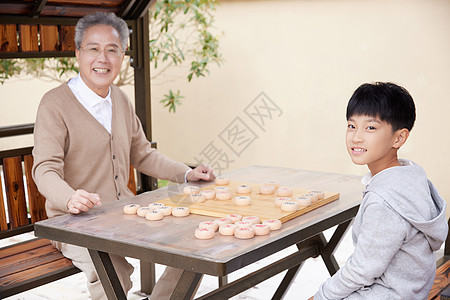 老年娱乐爷爷教孙子户外下象棋背景