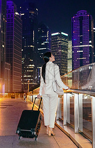 都市女性夜晚拉着行李箱独自在天桥上图片