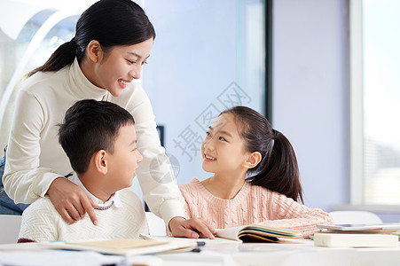 学生做作业年轻女老师辅导小朋友学习背景