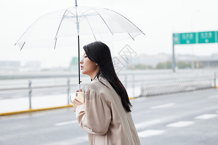 户外撑伞等侯的年轻女性图片