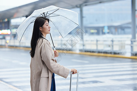 户外撑伞等车的女性图片