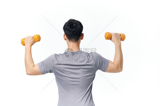 使用哑铃锻炼身体的男性背影图片