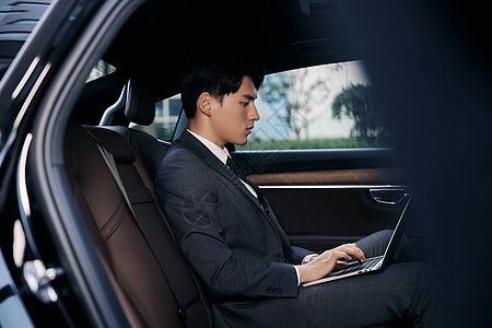 年轻商务白领坐在轿车里用笔记本电脑办公图片