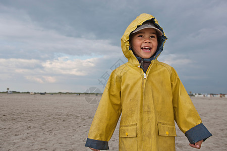 微笑的男孩在海滩上穿着雨衣背景图片