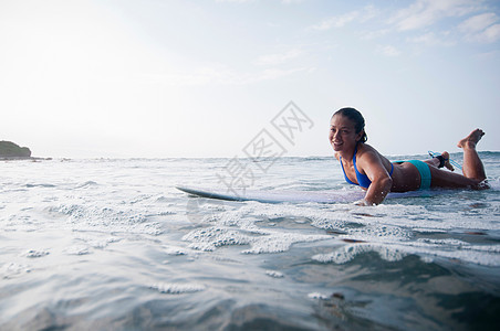 冲浪板上划水的女人图片