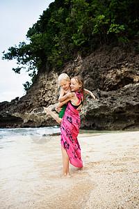 女孩在海滩上背着弟弟图片