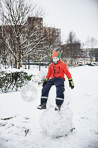 男孩坐在公园的雪人上图片