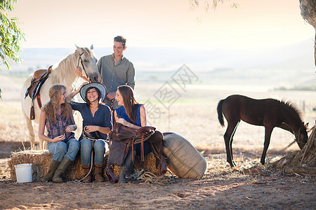 四个年轻的朋友坐在草地上骑着马图片