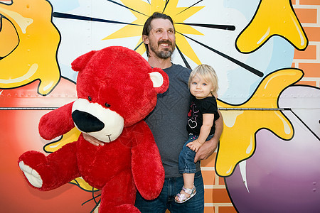 男人拿着大泰迪熊玩偶抱着儿子图片