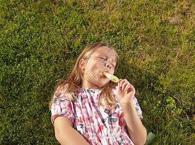女孩在草坪上吃冰棒背景图片