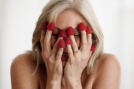 手指上戴着草莓罩住脸的妇女图片