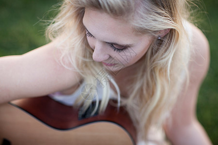 在草地上弹吉他的女人背景图片