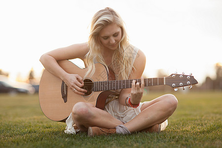 在草地上弹吉他的女人背景图片