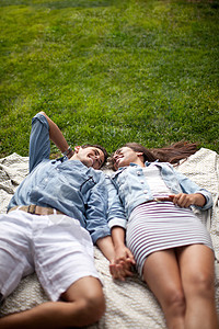年轻夫妇躺在野餐垫上手牵手图片