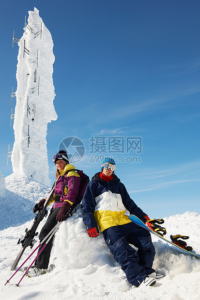 在山顶冰雕前休息的滑雪运动员图片