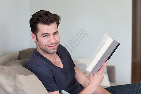坐在沙发上看书的成年男子图片