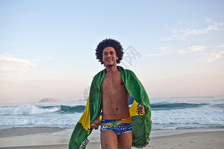海滩上身披巴西国旗的年轻人图片