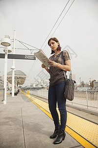 在车站等候时读报纸的女人图片