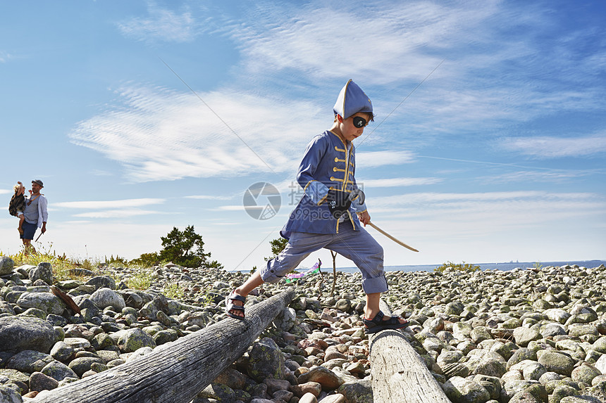 穿着海盗服饰的男孩在瑞典埃格隆海滩穿过木头