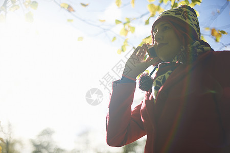 秋季公园里使用手机打电话的年轻女性图片