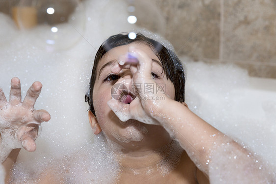 年轻男孩在浴缸中吹泡泡图片