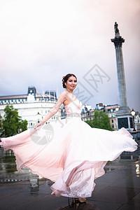 在英国伦敦Trafalgar广场的黄昏穿着晚礼服跳舞的年轻女子图片