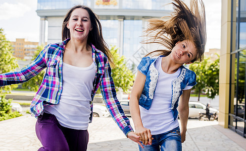 两名青年妇女一边摇头一边在城市奔跑图片